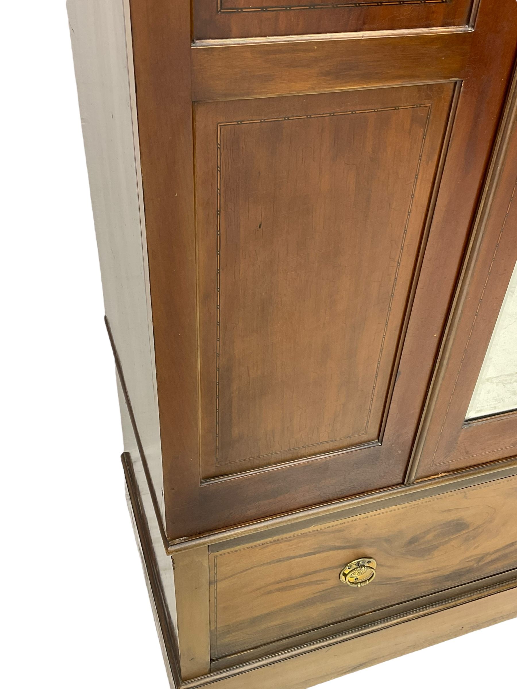 Edwardian inlaid mahogany wardrobe, projecting moulded cornice over central bevelled mirror glazed door, panelled uprights inlaid with trailing bellflowers and foliate decoration, the skirted base fitted with single drawer 