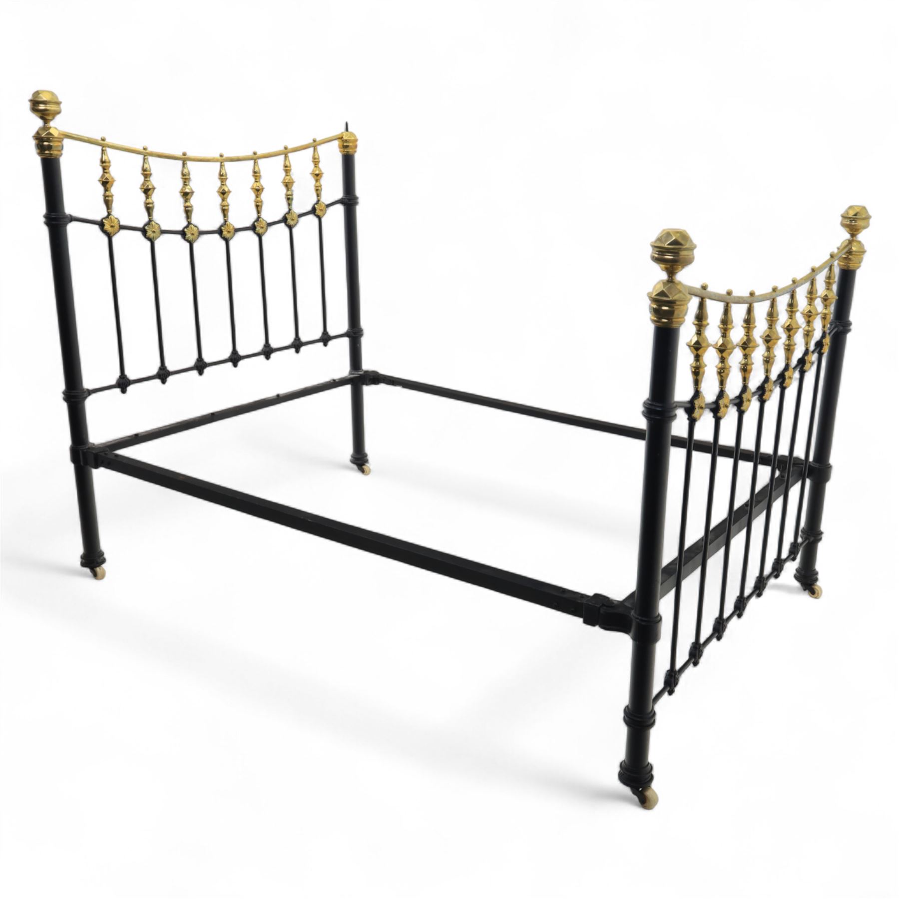 Victorian brass and iron 4' 6'' double bedstead, curved brass top rail with cast iron spindles and ornate floral rosettes flanked by urn shaped finials, foldable divan style base upholstered in a striped fabric, supported on turned posts and ceramic castors