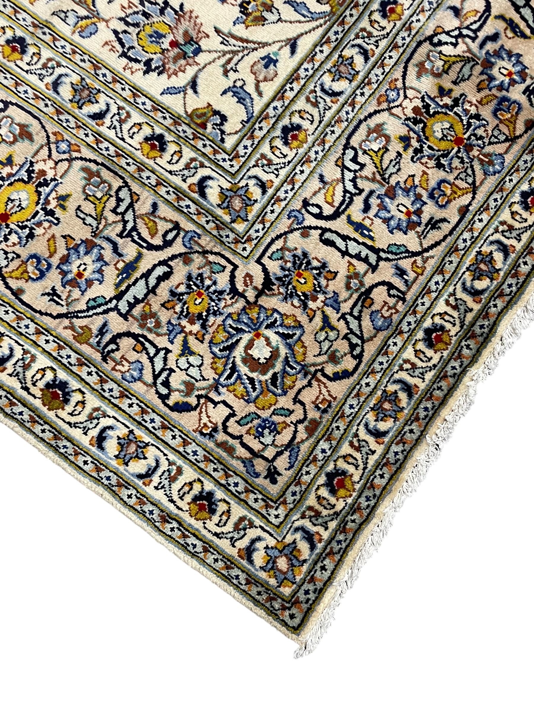 Persian Kashan Ivory ground carpet, the busy field decorated all over palmettes and trailing branches, scrolling border interspersed with stylised plant motifs, within guard stripes