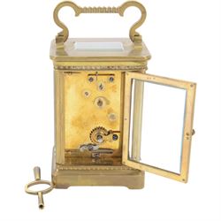 French-Edwardian 8-day timepiece carriage clock with a cylinder platform escapement, anglaise style brass case with four glass panels, dial with a polished gilt mask and foliate decoration, white enamel chapter with Arabic numerals and steel spade hands, . With Key. 