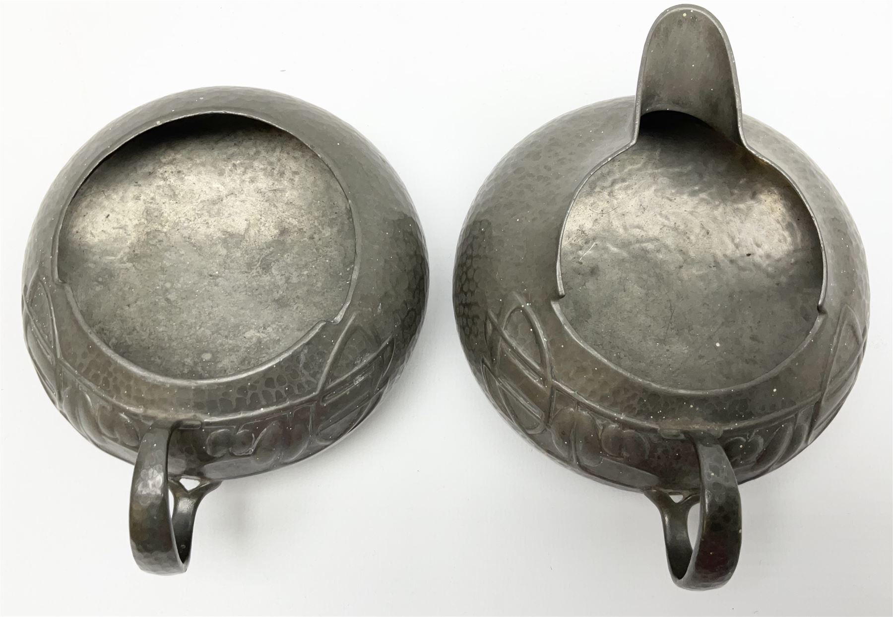 Archibald Knox for Liberty & Co Tudric pewter three piece tea service, comprising teapot with woven reed handle, single handled open sucrier, and milk jug, each with planished finish and detailed with honesty flowers, each impressed beneath Made in England Tudri Pewter 0231 