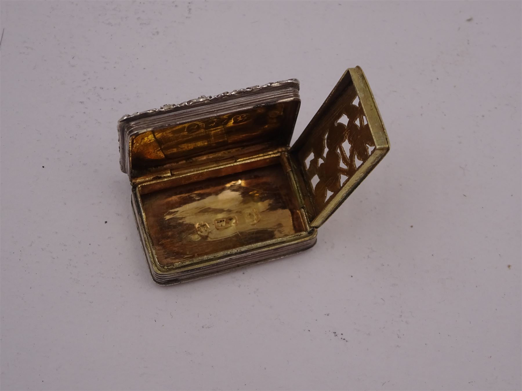 George III silver vinaigrette, of typical rectangular form, with raised foliate rim and engine turned decoration, with banded sides and foliate pierced engraving to gilt interior, hallmarked Birmingham 1797, maker's mark TS, L3cm