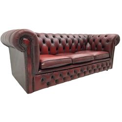 Chesterfield three seat sofa, upholstered in deep buttoned oxblood leather, on castors
