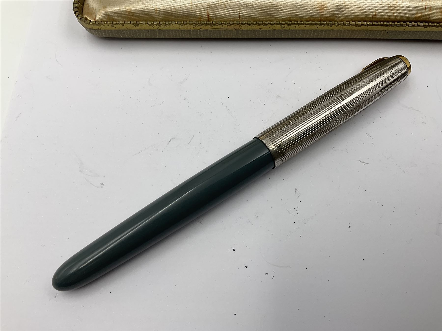 Three parker fountain pens, one example with 14ct gold plated cap and personal engraving, in Parker 51 box, together with a silver Sampson Mordan Everpoint propelling pencil with personal engraving and a silver cased fountain pen with 14ct gold nib and a souvenir bronze Dollfus-Mieg medallion, awarded to John G Sedorski, in fitted case 