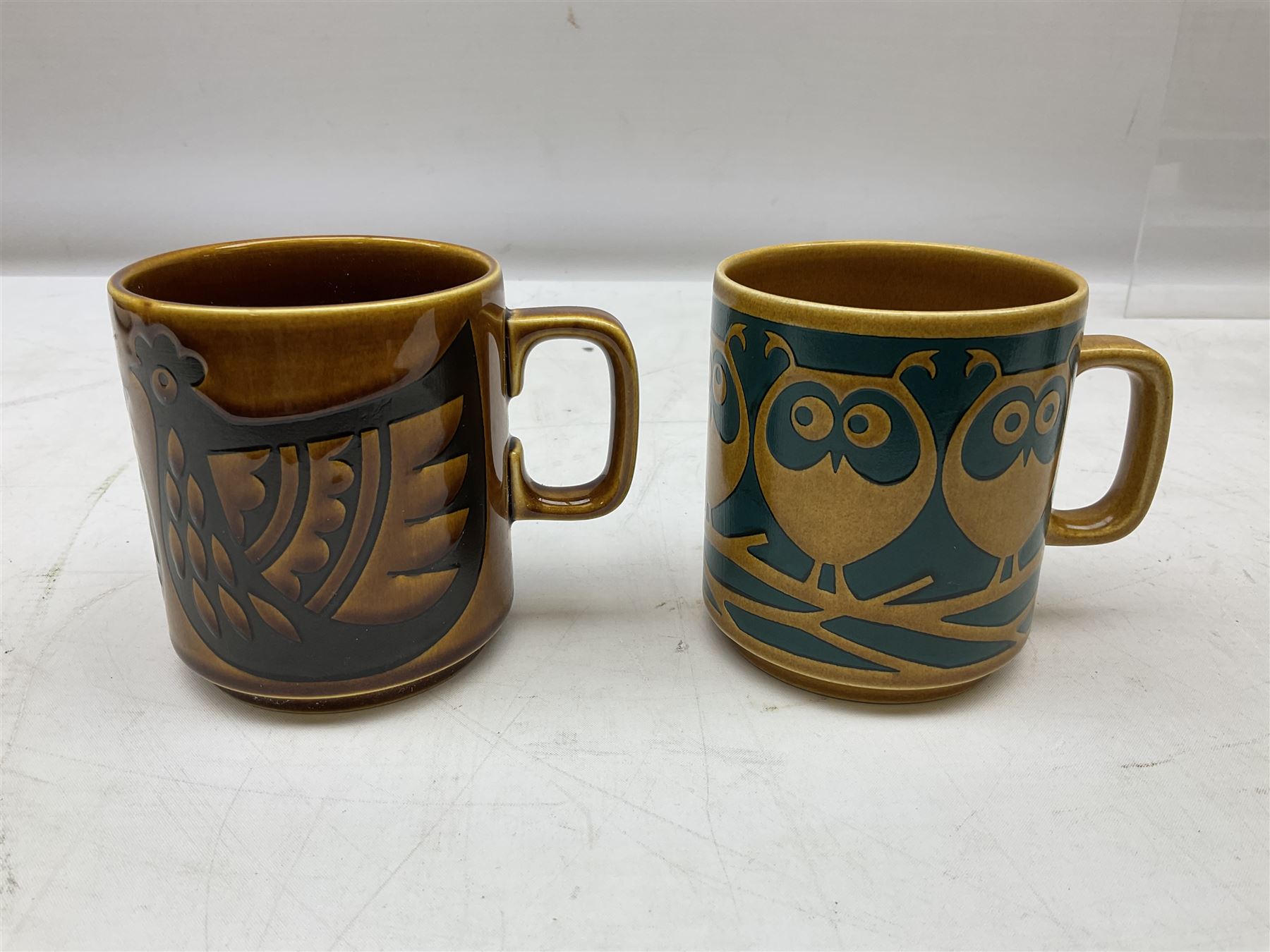 Collection of 1970s Hornsea mugs designed by John Clappison, comprising six Train Robber pattern examples together with owl patterned example on dark teal ground, and further example decorated with stylised hen and chick and egg, approx 9cm, together with four small cup bowls, all with stamped Hornsea marks beneath