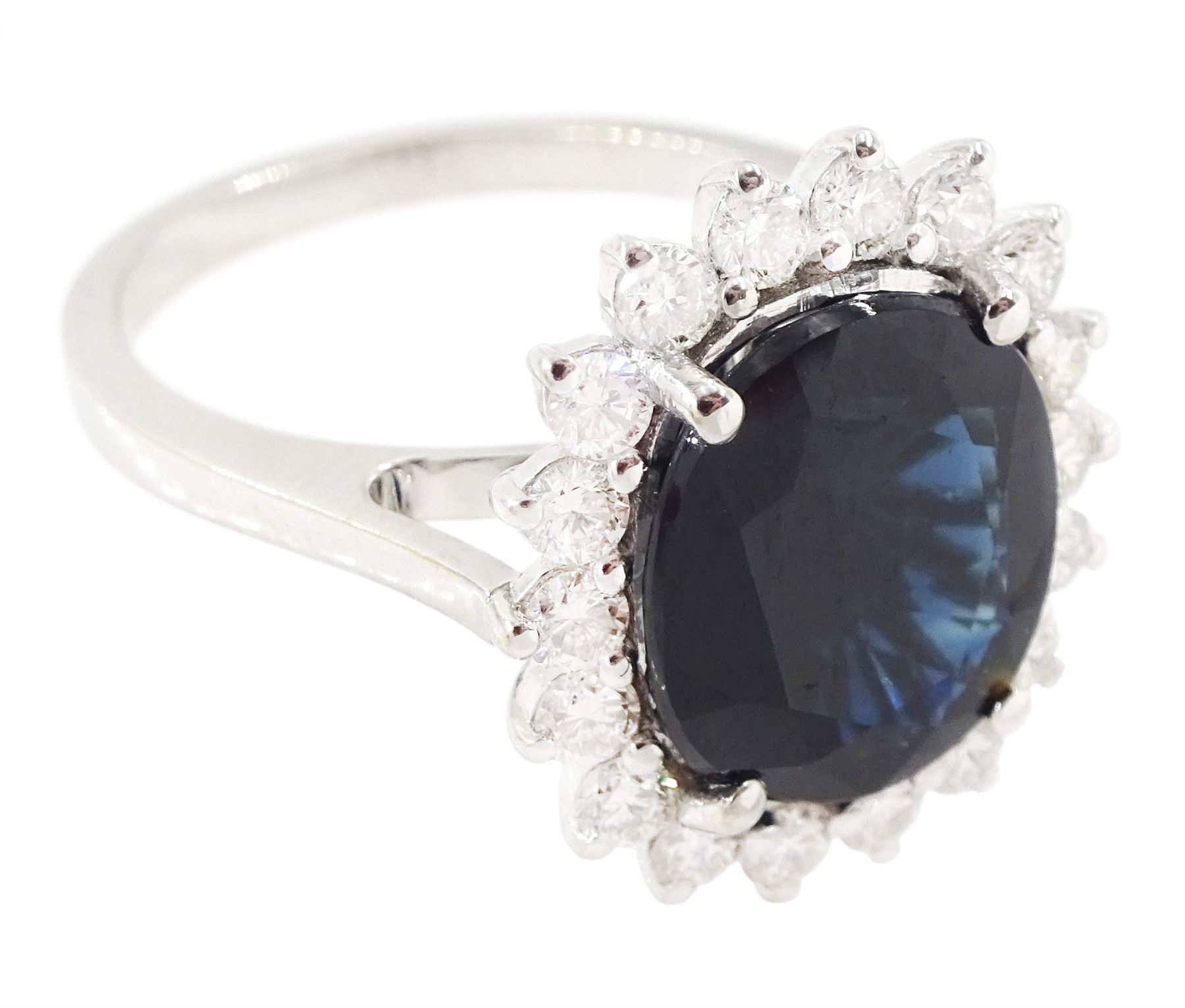 18ct white gold sapphire and diamond cluster ring, single oval cut sapphire of approx 4.30 carat, sounded by eighteen round brilliant cut diamonds, stamped, total diamond weight approx 0.75 carat