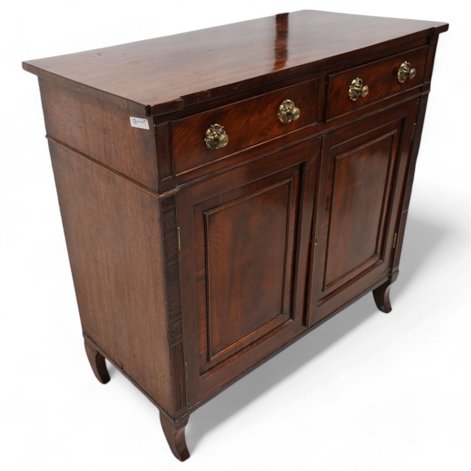 Regency mahogany cupboard, rectangular shaped top over two cock-beaded frieze drawers, fitted with brass Yorkshire rose pull handles, over two panelled and cross-banded cupboards, flanked by reeded uprights, raised on curved feet