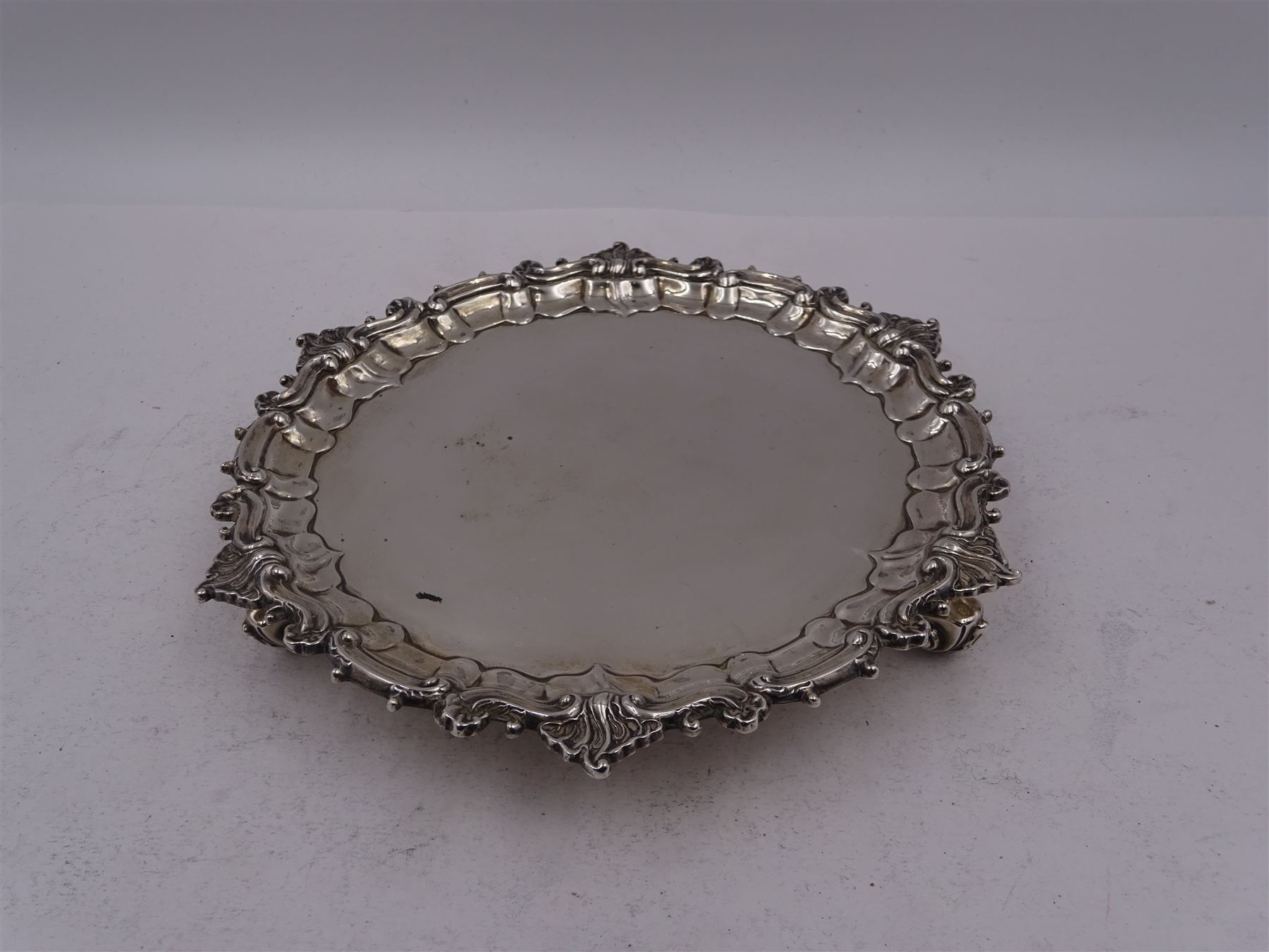 Victorian silver waiter, of typical form, with shaped rim embossed with C scrolls, upon three scroll feet, hallmarked Sibray, Hall & Co, London 1898, D18.5cm