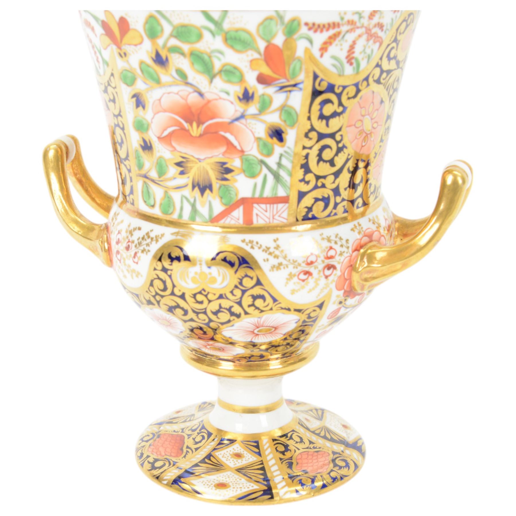 Royal Crown Derby campana vase, decorated in imari pattern, with gilt handled upon a circular base, with mark beneath, H22cm