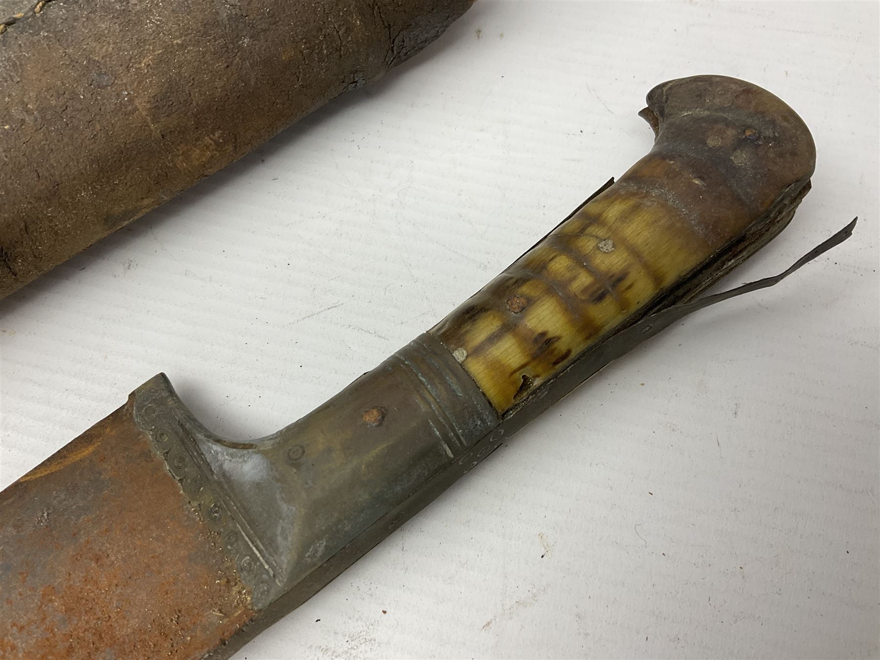 Mandingo sword, the 63cm plain curving steel blade marked with a horses head and the initials G.S.; leather covered grip with metal ribbed spherical pommel; in decorative leather leaf scabbard mounted with tassels and roundels L84cm overall; and a North African flyssa sword in poor condition with wooden scabbard (2)