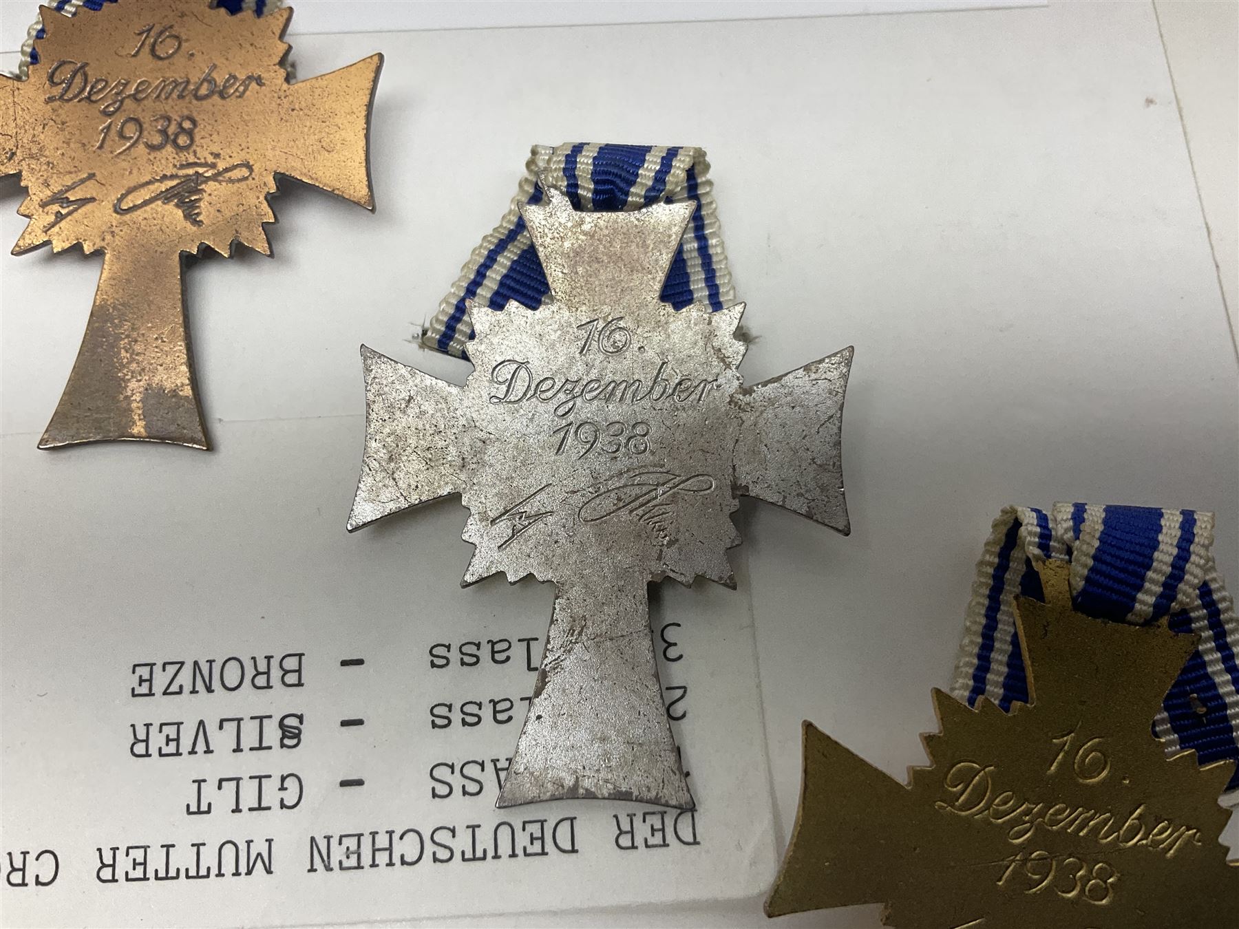 WWII set of three German Mother's Crosses, 1st Class in gilt, 2nd Class in silver and 3rd Class in bronze; all with ribbons (3)