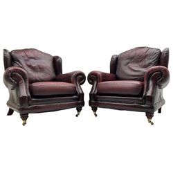 Thomas Lloyd - three-piece lounge suite, comprising of traditional shape two seat sofa (W190cm H80cm) and a pair of wingback armchairs (W100cm H91cm), each with rolled arms over turned supports with brass castors, upholstered in oxblood red leather