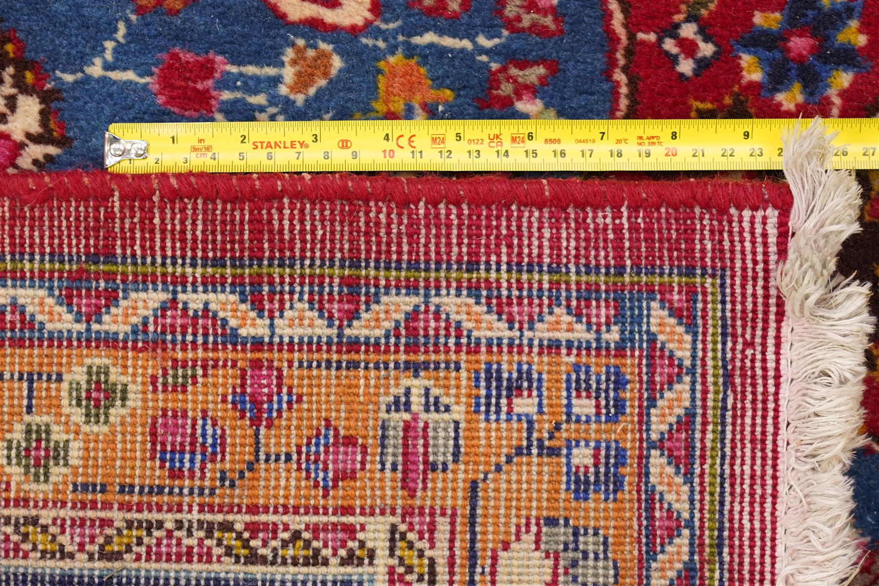 Persian Kashan hand-knotted rug, madder red ground centred by circular floral medallion with pendants, surrounded by scrolling vines, palmettes and flowerheads, dark navy spandrels, enclosed by dark navy floral border with multiple guard stripes