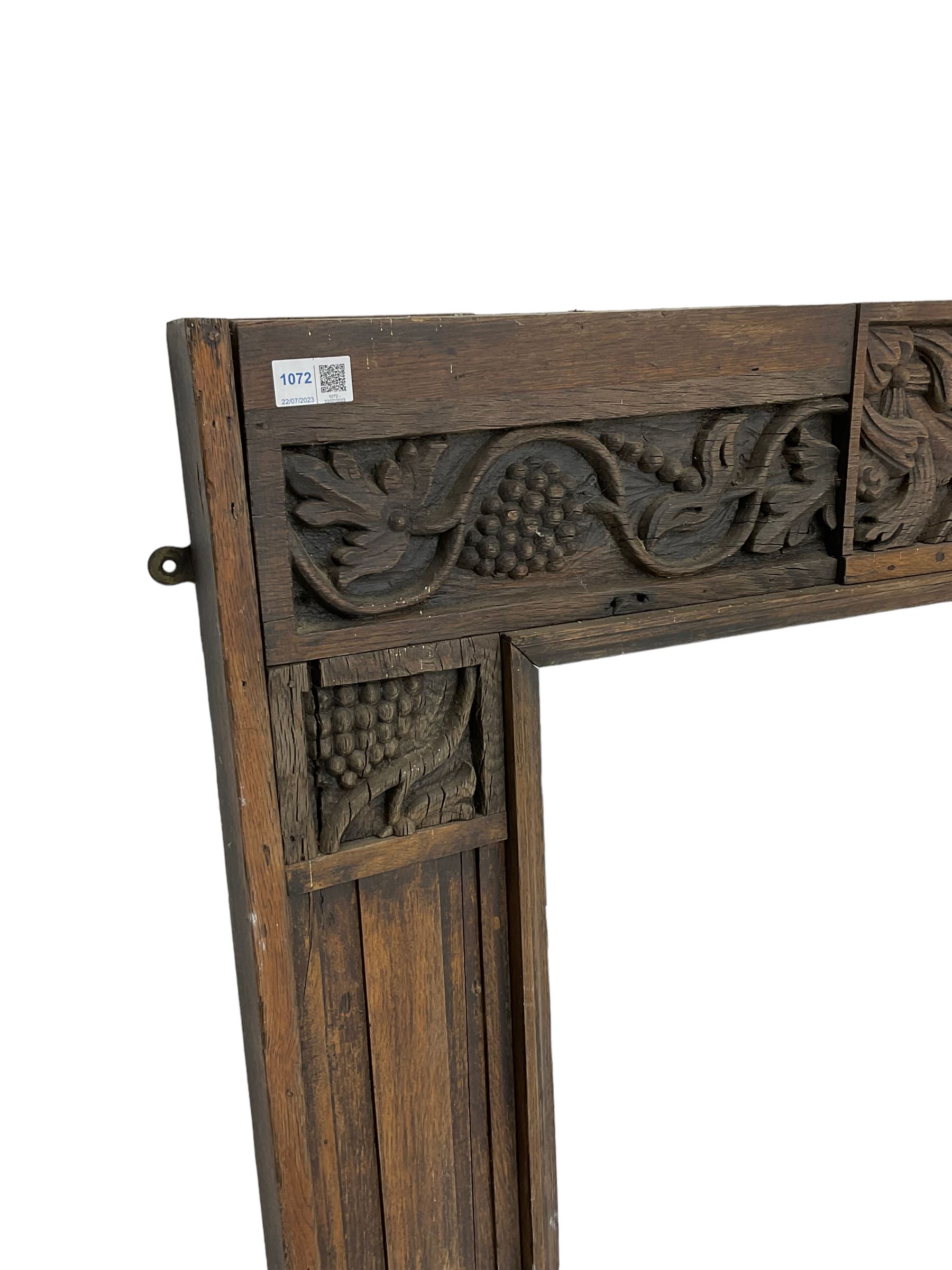 19th century Jacobean Revival oak fire surround, decorated with applied carved panels depicting foliate patterns and stylised grape vines, uprights carved with fleur-de-lis decoration