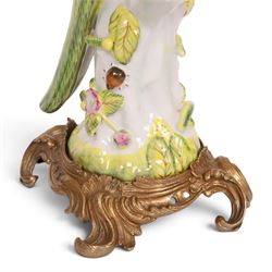 Pair of candlesticks, modelled as green parrot upon a flowering branch, upon four gilt acanthus leaf feet, H36cm