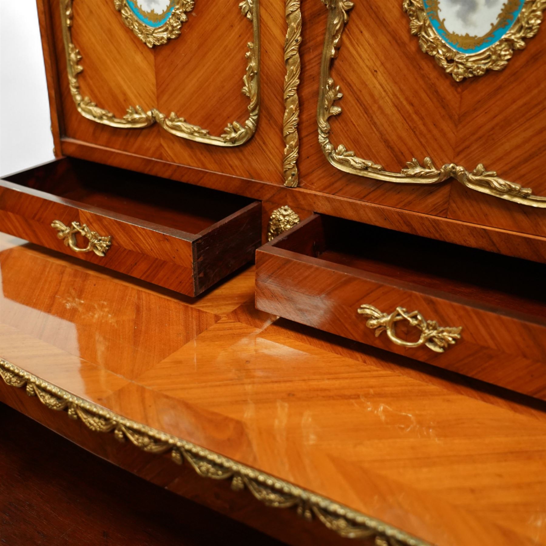 Late 19th century French Louis XV style kingwood and ormolu mounted bonheur du jour, the upper section with a pierced three-quarter gallery over a pair of cupboard doors inset with Sèvres-style porcelain portrait plaques, enclosing a shelved interior over two short drawers, the serpentine top and apron richly mounted with gilt-bronze foliate and scroll motifs, single frieze drawer below on cabriole supports with acanthus cast sabots
