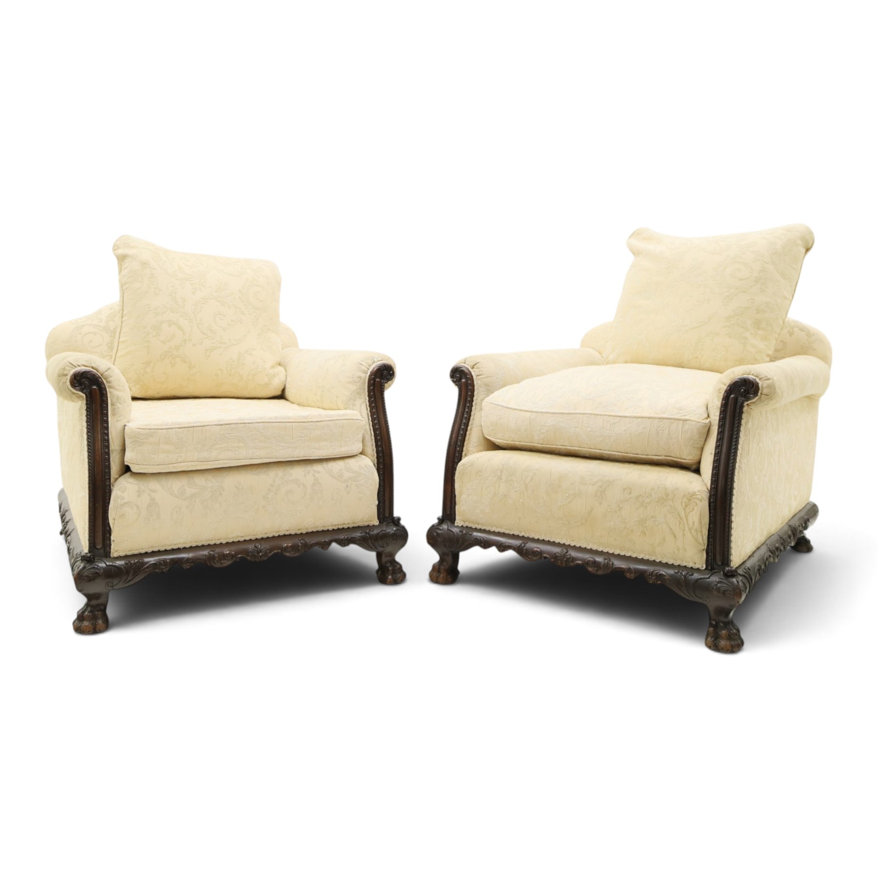 Quality Edwardian carved mahogany lounge suite comprising three-seater settee and pair of armchairs, the sofa with arched back over rolled arms and deep sprung seat, the arm terminals carved with acanthus rosette over gadroon and rope-twist moulding, the shaped apron carved and moulded with scrolling foliate acanthus motifs, terminating to four large front hairy paw and ball feet, upholstered in pale yellow foliate fabric with matching seat and scatter cushions (W200cm D105cm H73cm); the matching deep armchairs (W78cm D95cm H75cm)
