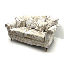 Two seat sofa upholstered in a pale gold ground fabric with floral pattern, shaped cresting rail, scrolling arms