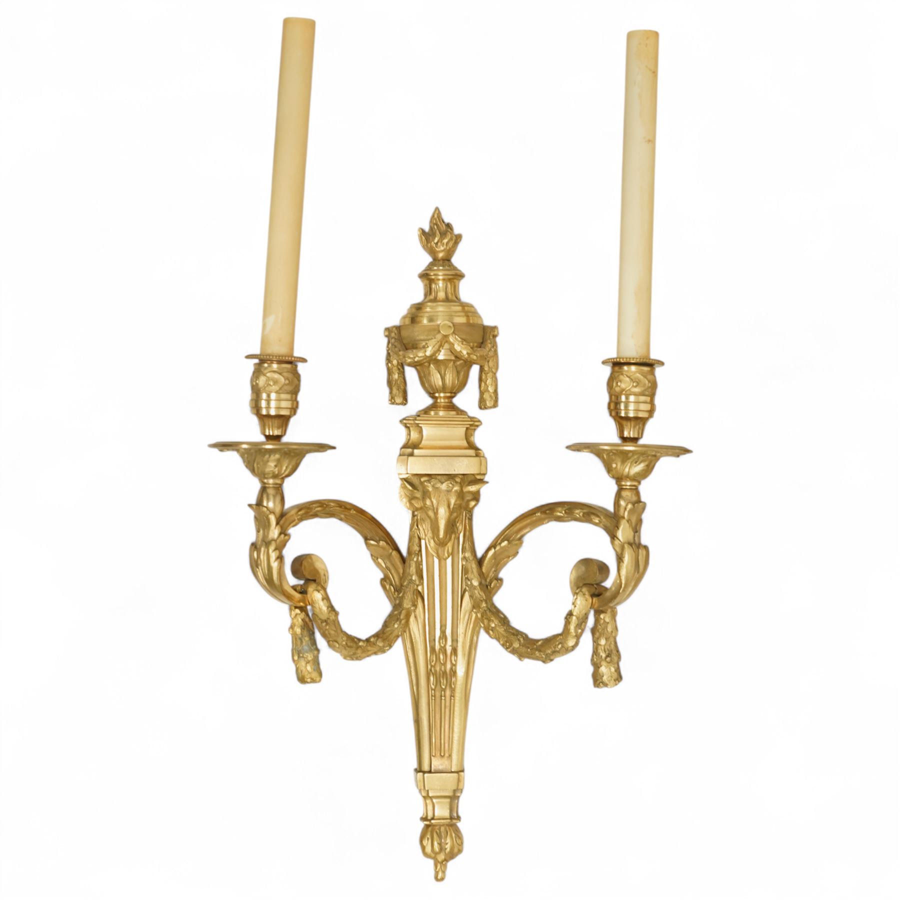 Pair of 19th-century Louis XVI-style ormolu rams-headed two-light wall appliques, the arms joined by a garland of laurel leaves, the half fluted stem surmounted by a vase with laurel garland, wired for electricity 