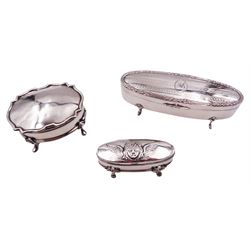Early 20th century silver dressing table box, of oval form, the hinged cover with engraved monogram to centre, engine turned decoration and flower head and reeded border, upon four pad feet, hallmarked William Adams Ltd, Birmingham 1917, W12.5cm, together with two further early 20th century silver examples, the larger example of oval form with shaped rim, hallmarked Lee & Wigfull, Sheffield 1913, W7.5cm, the smaller also of oval form, the hinged cover repoussé decorated with putto mask, hallmarked Henry Matthews, Birmingham 1905, W7cm, approximate total weight (not including liners which are loose) 4.51 ozt (140.4 grams)