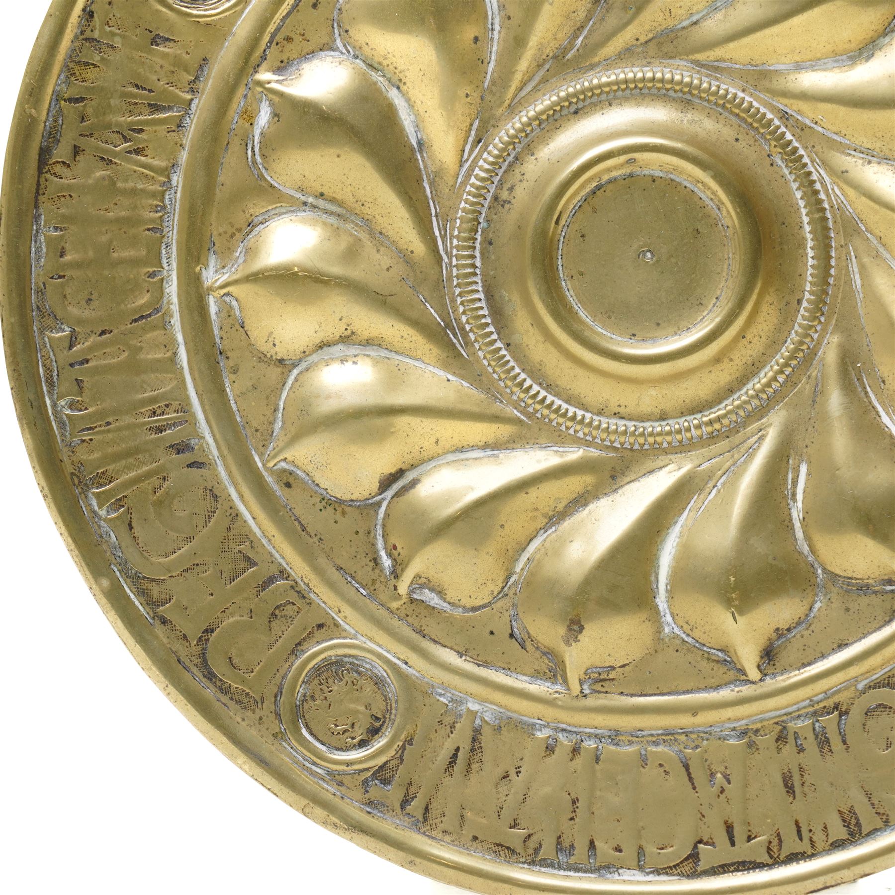 Central section of a 17th century Nuremberg brass alms dish, central rosette surrounded by Gothic inscription, intersected by roundels with engraved heads, D23cm 