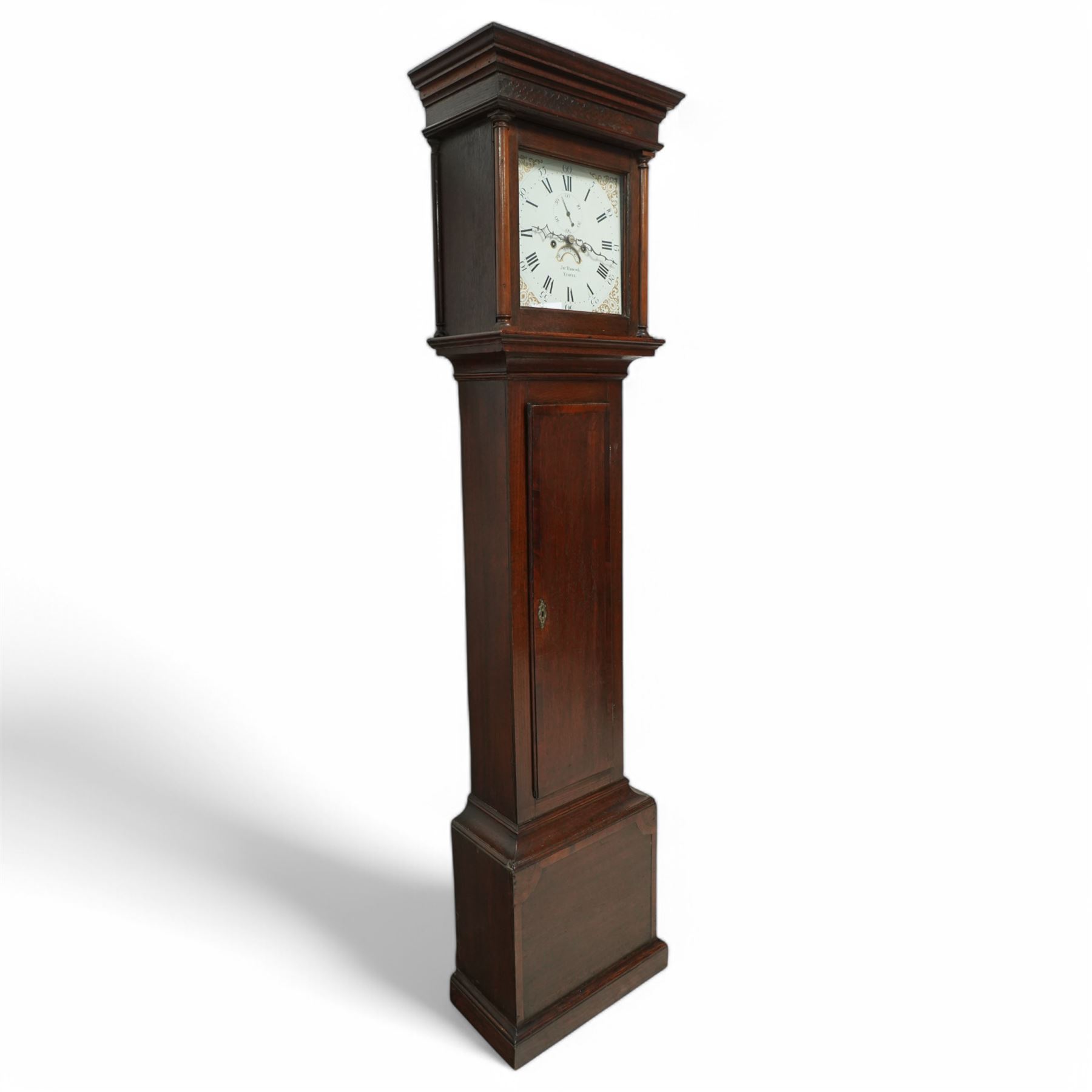 John Hancock of Yeovil (Sommerset) - oak cased 8-day longcase clock c1810, with a flat topped pediment, blind frieze and broad cornice, square hood door with attached wooden pilasters and capitals, long trunk door on a square plinth with applied skirting, painted dial with steel hands, gilt painted spandrels, Roman numerals, minute track and five-minute Arabic's, with seconds dial and date aperture, dial pinned via a falseplate to a rack striking movement, striking the hours on a bell. With weights and pendulum.
