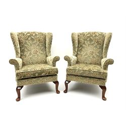 Pair Parker Knoll mid 20th century classic wing back armchairs, upholstered in beige floral patterned fabric, raised on cariole supports