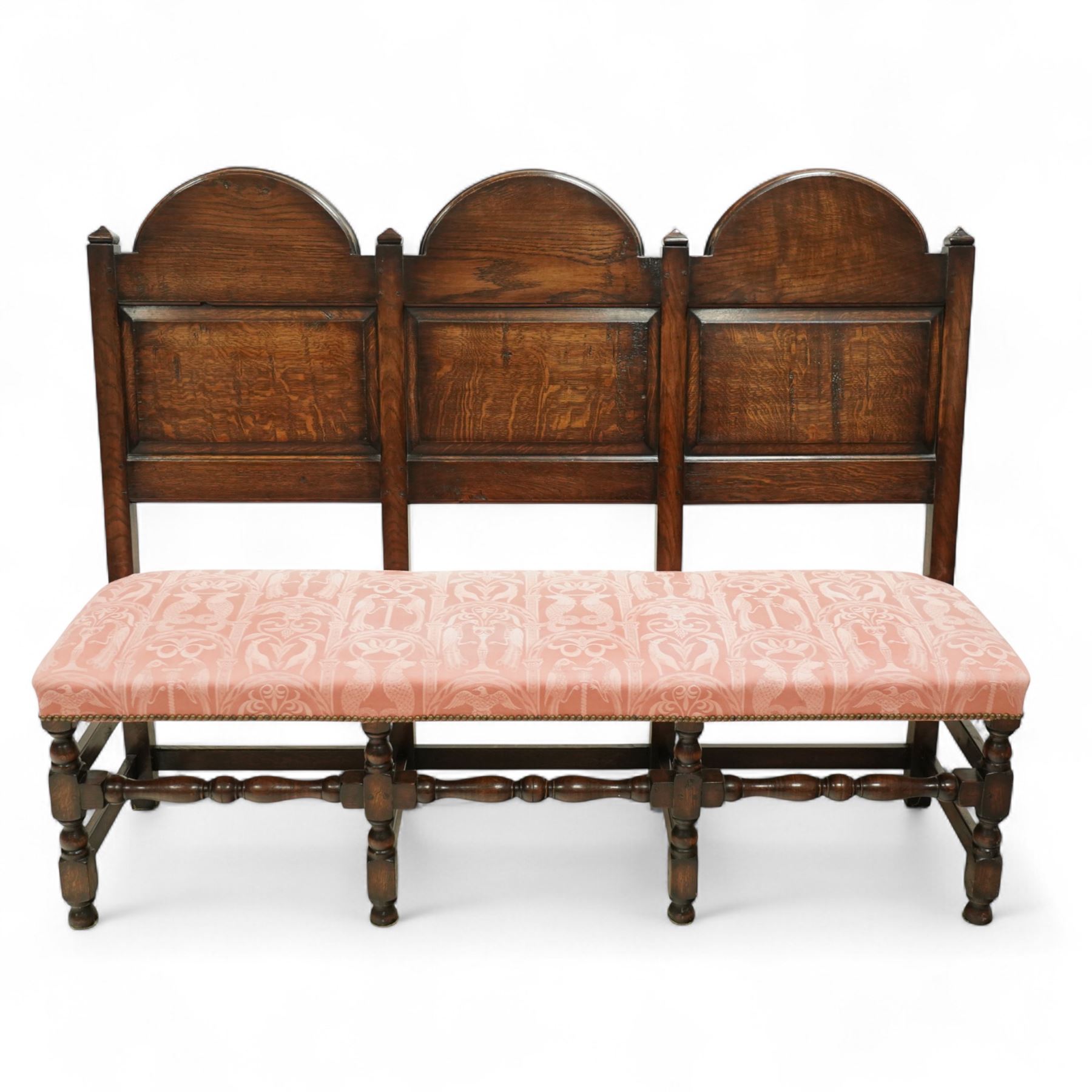 Bylaw of Ross On Wye - 17th-century design oak three-seat hall bench, triple arched panelled back, padded seat upholstered in pink damask fabric, raised on turned baluster legs united and turned front stretcher