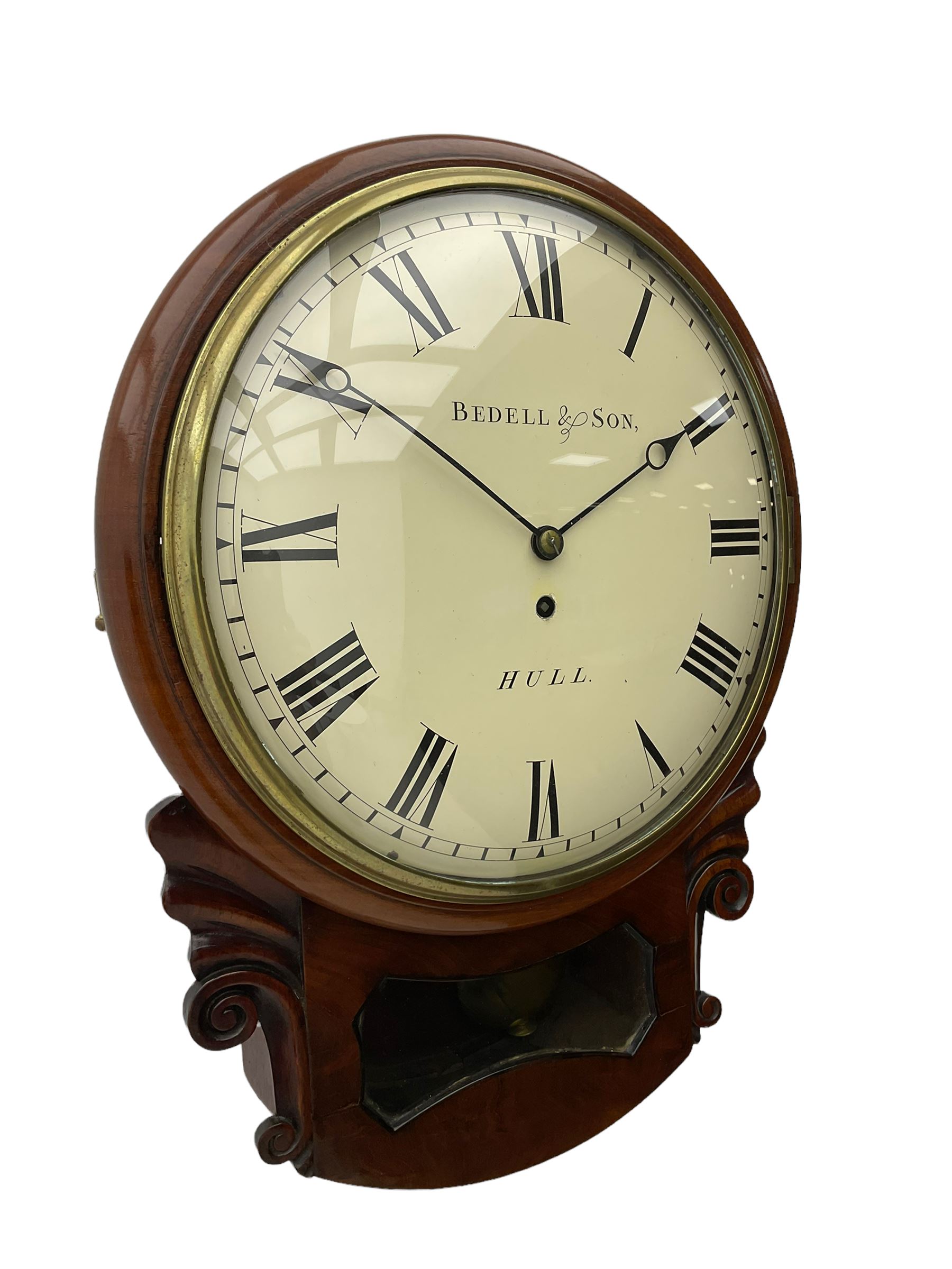 A single fusee 8-day drop dial mahogany cased wall clock, c1860 with a 14-1/2” wooden bezel and 12” painted convex dial, cast brass bezel and convex glass, dial with retailer's name “Bedell & Son, Hull”, Roman numerals, minute track and matching steel moon hands, with a recoil anchor escapement and rectangular movement plates, case with scroll carved ears and glazed pendulum aperture, pendulum location door and a pendulum regulation door to the curved base. With pendulum.
***Peter and Benjamin Bedell were a family of 19th century Hull clockmakers working from various locations in Hull between 1823 and 1872.
