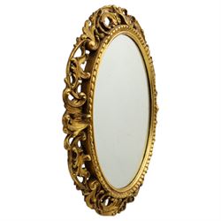 Late 19th century giltwood oval wall mirror, the bevelled plate within a gadroon moulded inner slip, surrounded by pierced scrolling foliate and acanthus carved frame, richly gilded with worn patina indicative of age and use