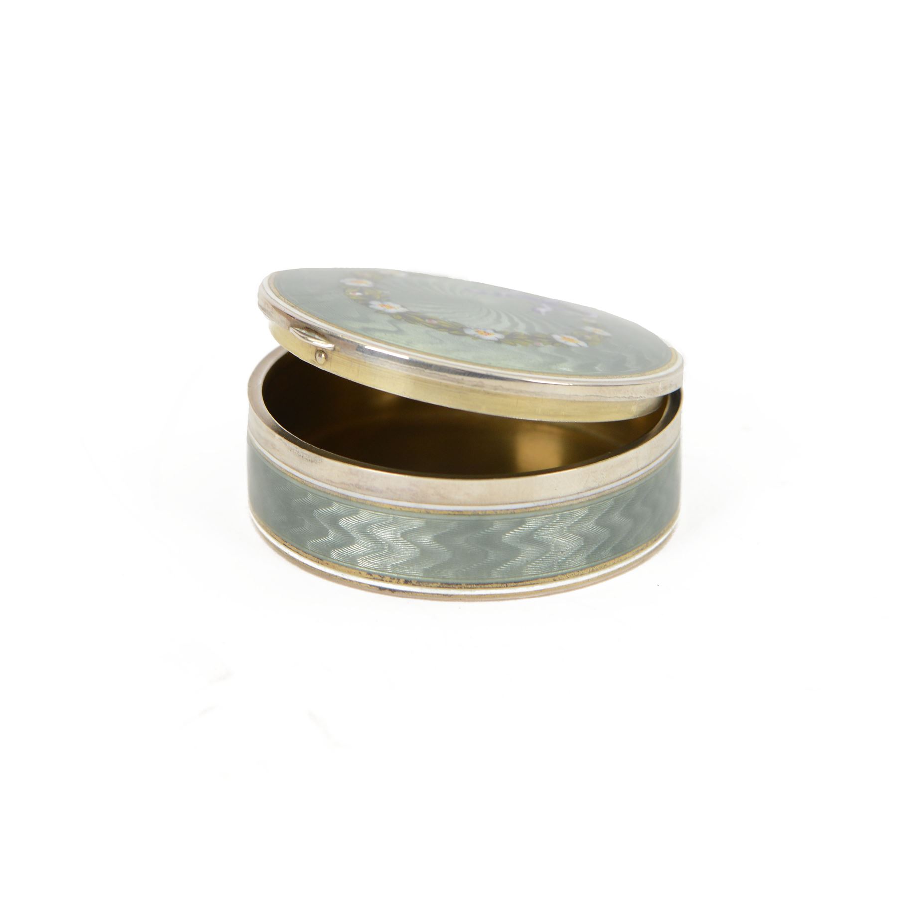 Early 20th century silver and guilloche enamel trinket box, of circular form, decorated throughout with pale green guilloche enamel and a floral wreath to the hinged cover, opening to reveal a gilt interior with personal engraving, import marks for Erich Kellerman, London 1909, D6cm