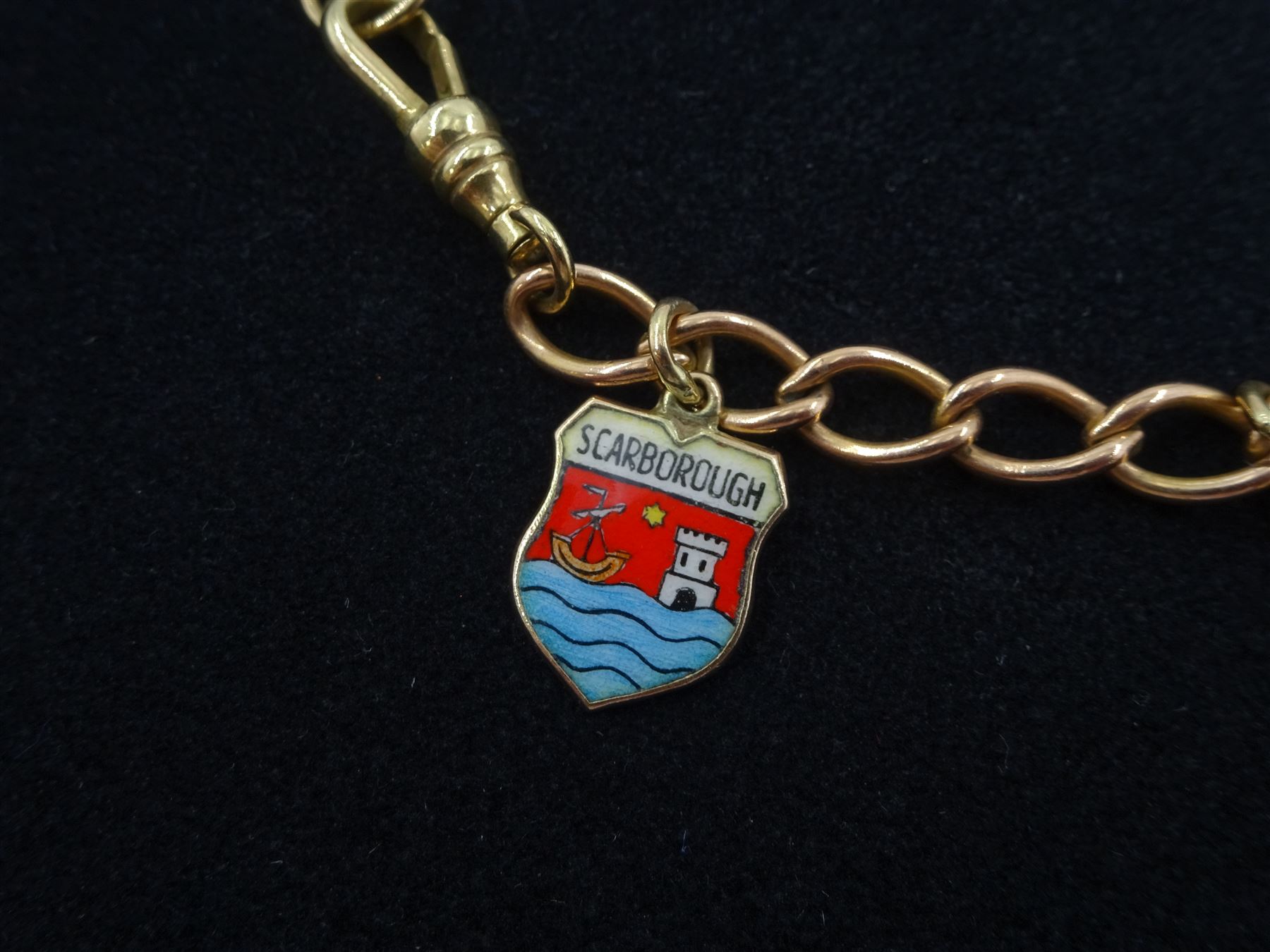 9ct rose gold curb link charm bracelet with yellow gold clip and four 9ct gold charms including, horseshoe, clown, bananas and enamel Scarborough charm