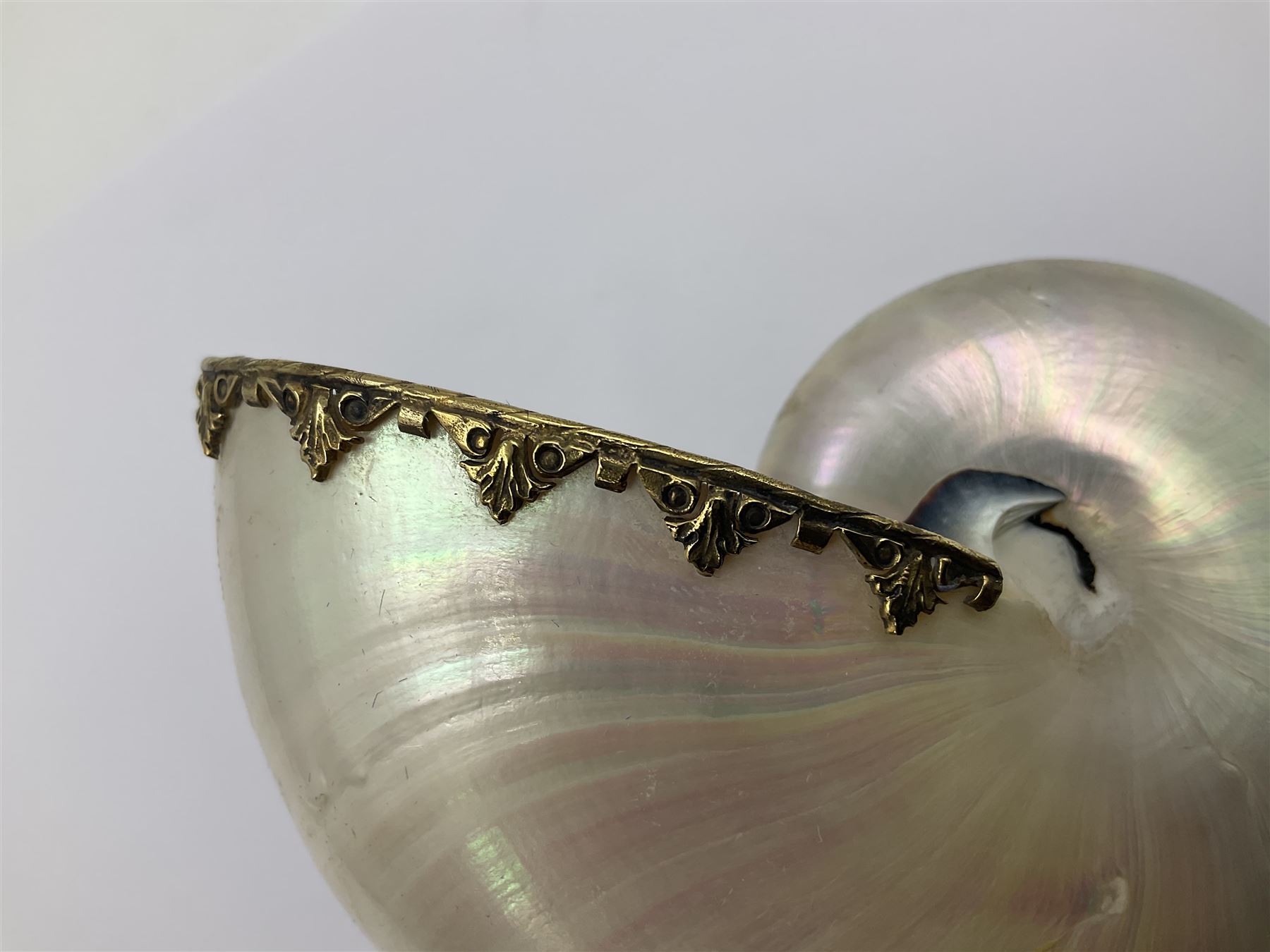 Modern limited edition silver mounted nautilus shell cup, no. 42/150, the pearlescent shell cup with silver-gilt strapwork to rim, upon a stem modelled as a putto supporting a gilt cornucopia and circular domed foot depicting Poseidon amongst swirling waves, hallmarked by St James House Company, London 1980,  H17.5cm