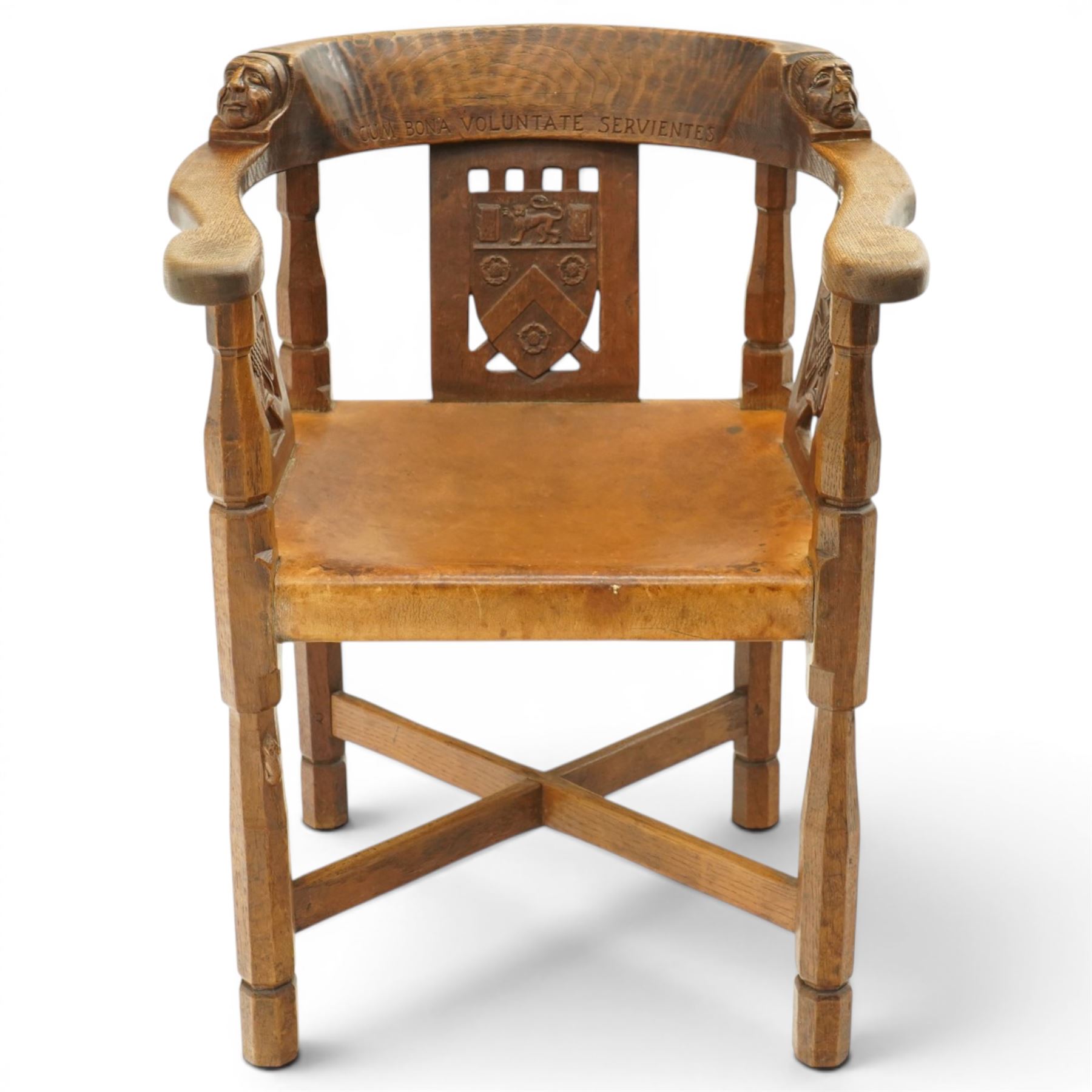 Mouseman - important oak monks chair, c1930s, the curved back inscribed with motto 'Cum Bona Voluntate Servientes' (serving with goodwill) over Trinity College Cambridge coat of arms, the shaped arms terminating with carved monks heads, each pierced side panel with Yorkshire Rose, tan leather seat on four octagonal legs joined by a cross stretcher, the back of the chair with initials ECH, with carved mouse signature, by Robert Thompson of Kilburn