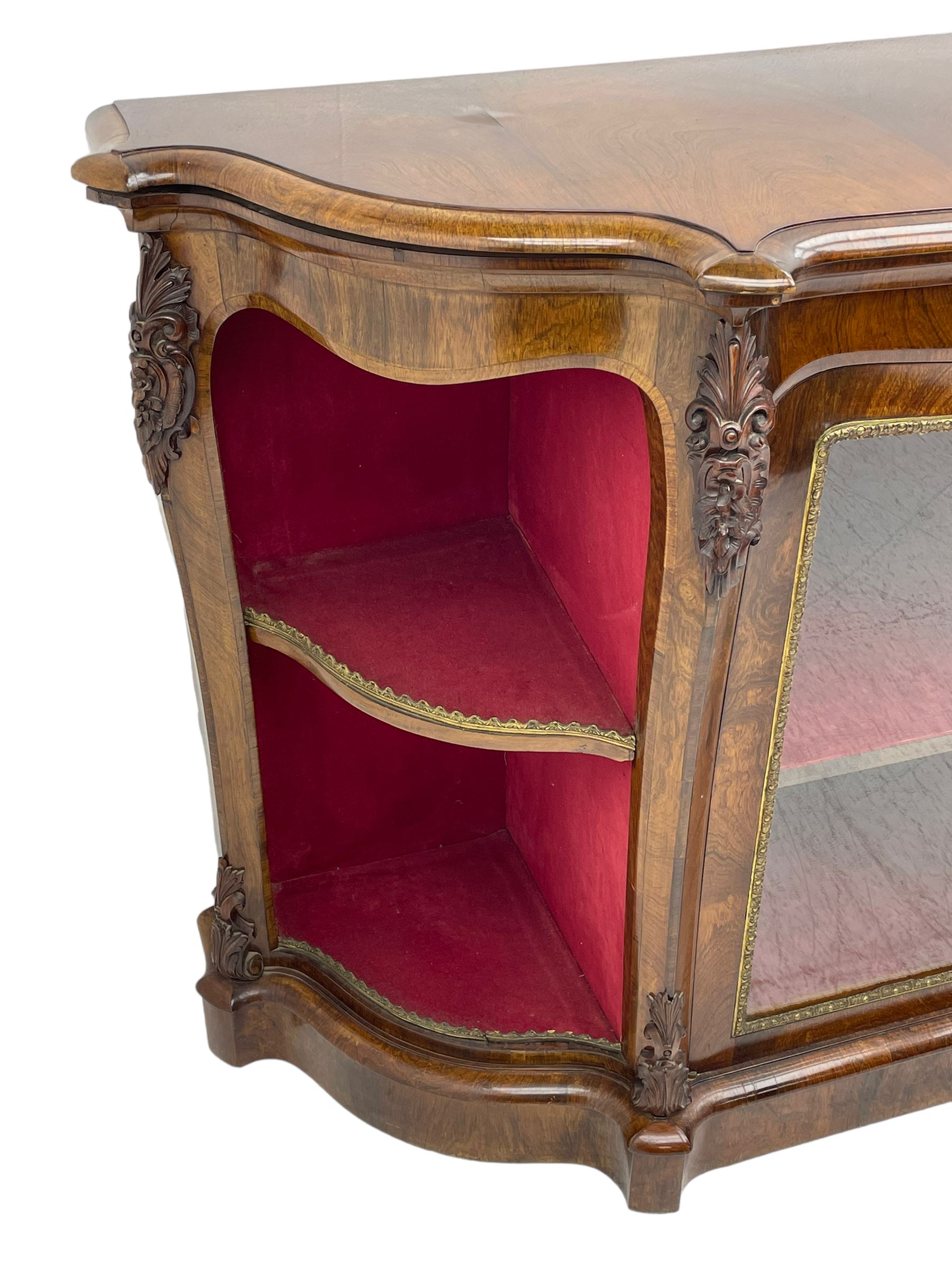 19th century rosewood buffet credenza, bombe form with shaped and moulded top, two central glazed doors with foliate moulded gilt slips, the red fabric-lined interior fitted with a single shelf, flanked by open shelves with raised gilt metal lips, the uprights decorated with shell and flower head carved cartouche mounts, acanthus leaf scroll carved lower mounts, on shaped and moulded plinth base 