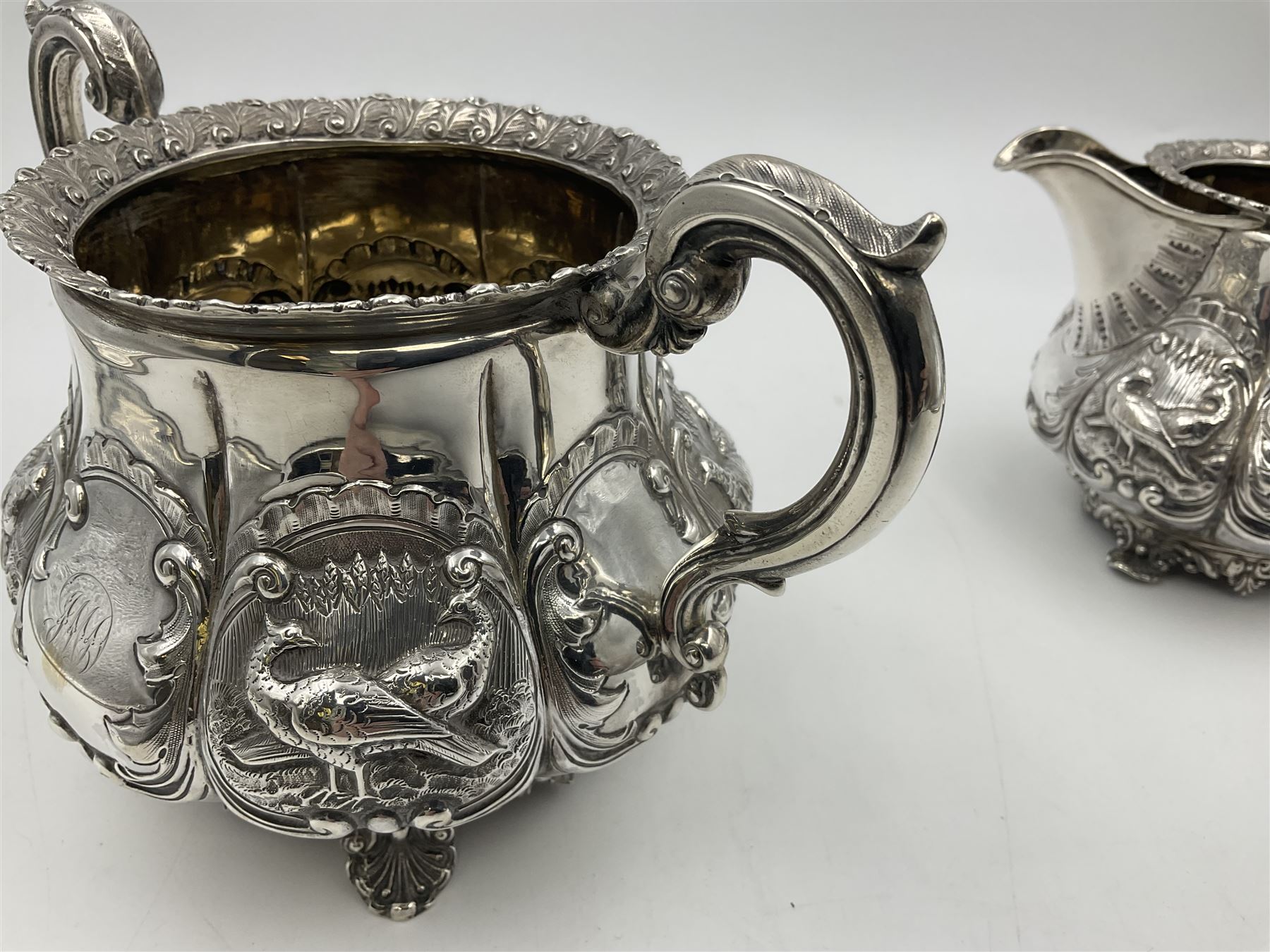 Victorian silver three piece tea service, comprising teapot, twin handled open sucrier, and milk jug, each of bellied form with acanthus capped scroll handles, the sides embossed with alternating scroll edged vacant panels and panels containing a pair of birds, upon four palmette feet, the teapot with ivory insulators to handle, and bird finial to the hinged domed cover, hallmarked William Hunter & Son, London 1861, teapot H19cm, including handles sucrier H13.5cm, including handle milk jug H12cm

This item has been registered for sale under Section 10 of the APHA Ivory Act