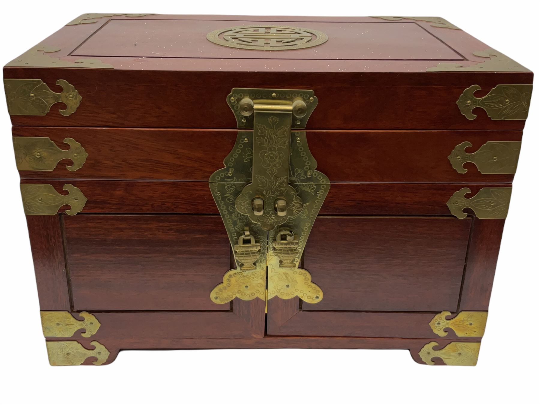 Chinese hardwood jewellery box mounted with engraved brass fixtures, the two exterior doors revealing three drawers below the hinged upper lid, lined with red material decorated with floral sprays, H25cm, W36cm, D23cm
