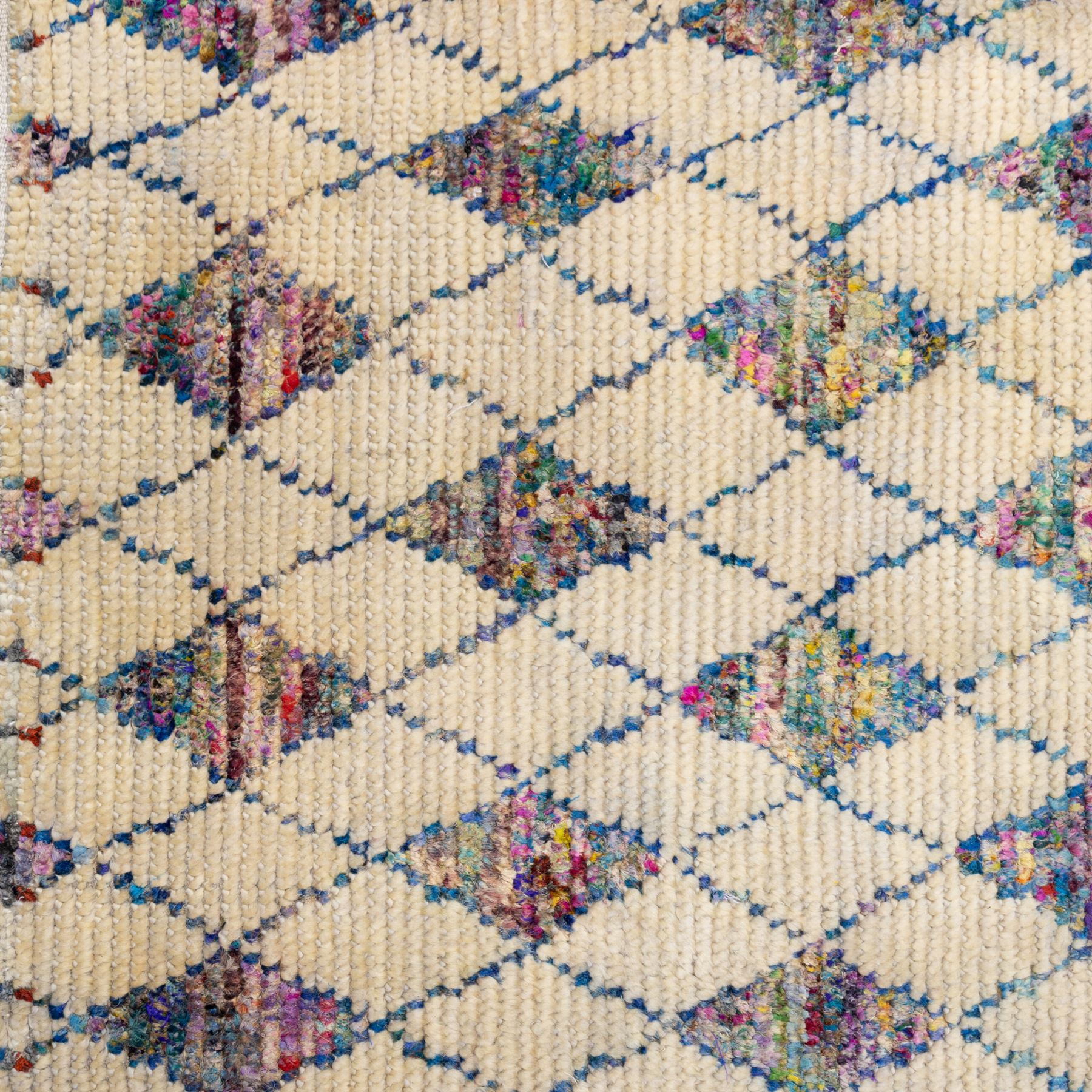 Contemporary Moroccan Berber design wool rug, cream field with blue diamond lattice, decorated with repeating multicoloured lozenge motifs, short fringe ends and bound sides