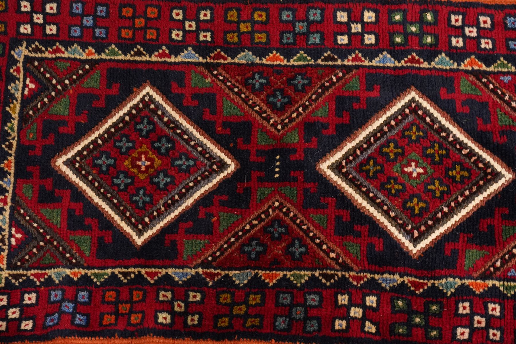 Two hand-knotted rugs, comprising Persian runner and Turkoman prayer rug, Persian hand-knotted runner, red and dark navy ground with four diamond medallions and geometric motifs, enclosed by multicoloured geometric border, striped kilim ends with fringes, H244cm, W58cm; Turkoman hand-knotted prayer rug, ivory mihrab field decorated with repeating stylised geometric motifs, enclosed by multiple geometric borders in madder red and brown, with fringed ends, H150cm, W93cm