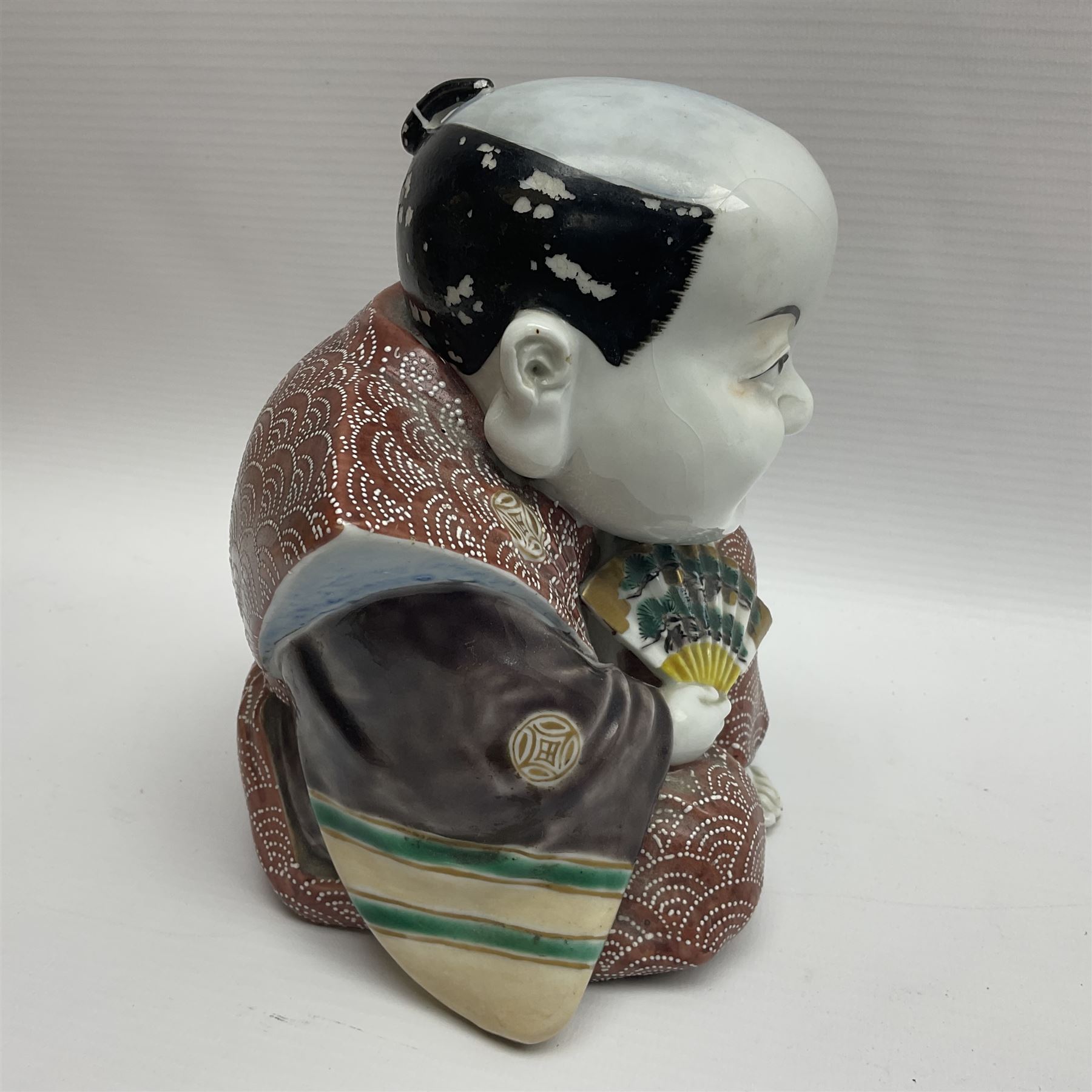 Japanese Fukusuke good fortune figure, modelled as a kneeling male figure holding a fan, dressed in traditional Samurai robes, H15.5cm