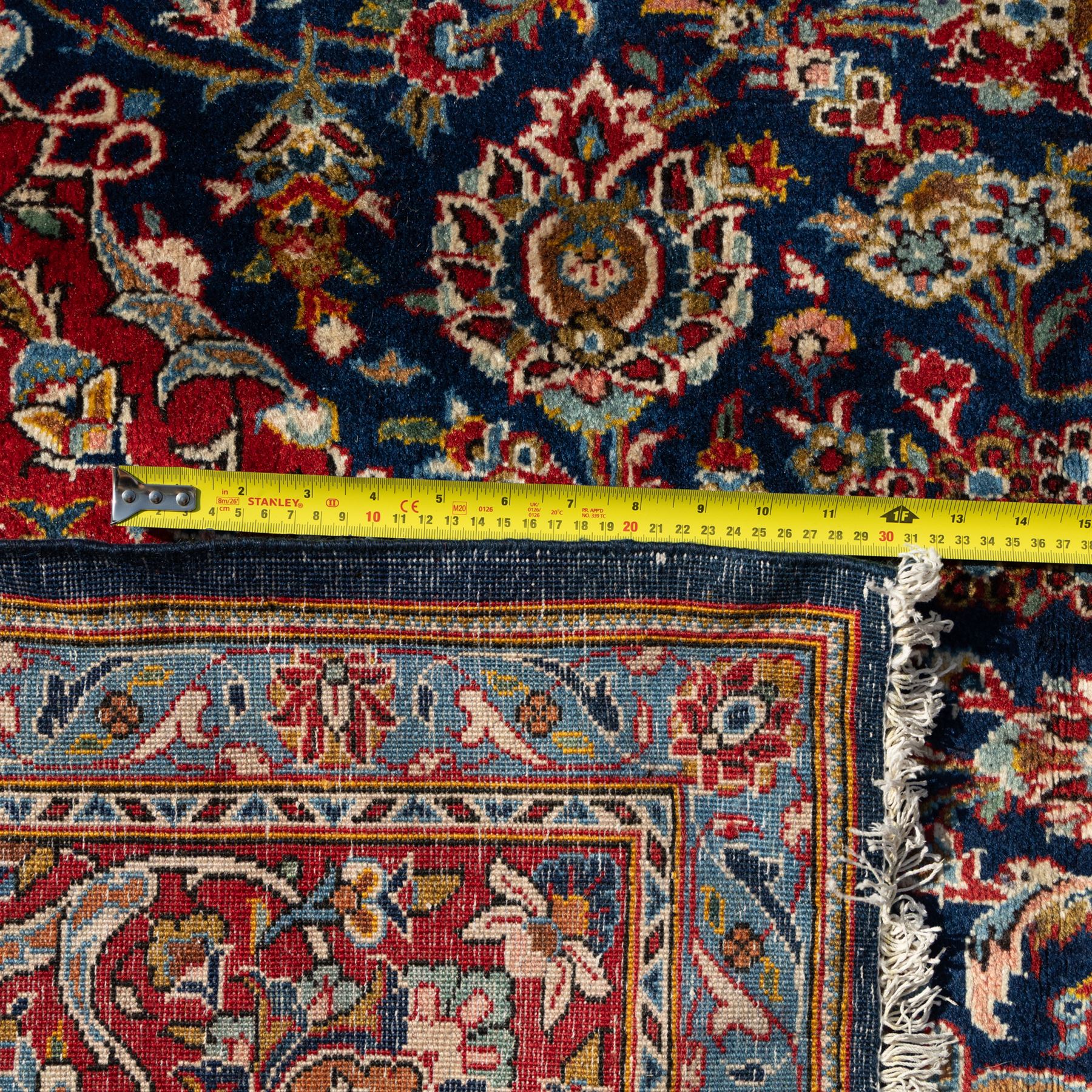 Persian Kashan carpet, navy field with central red diamond medallion enclosing floral rosette, framed by dense scrolling foliage and palmettes, triple borders in red, blue and ivory, originating from central Iran