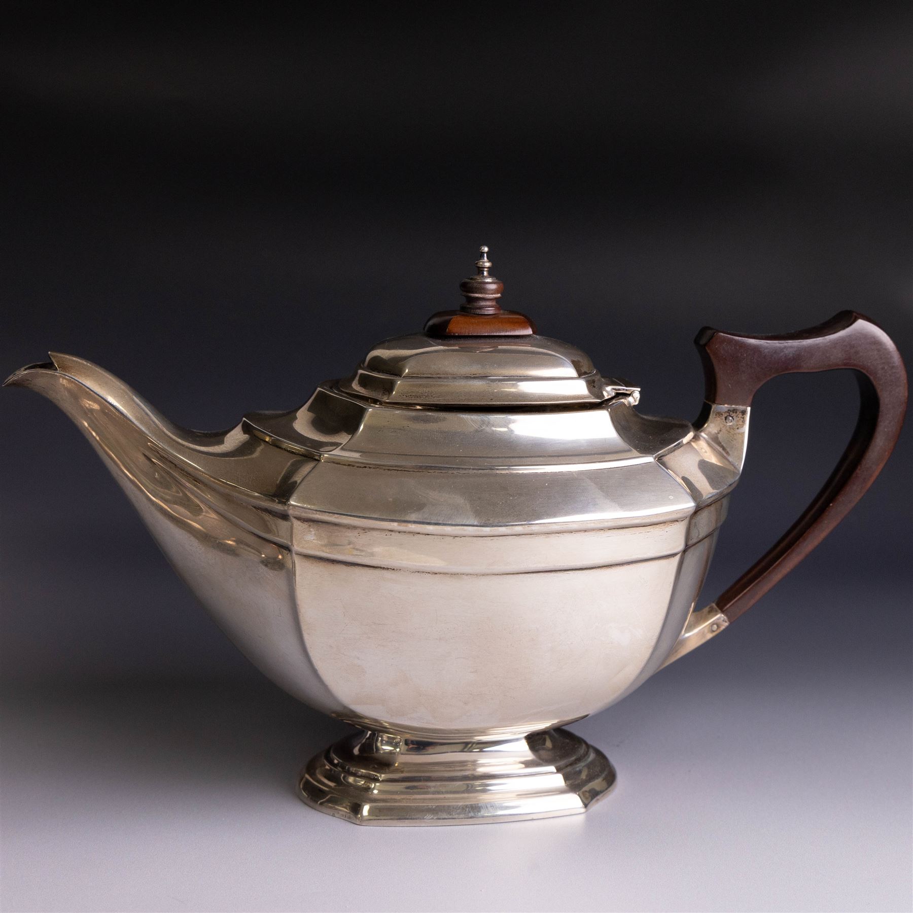 Art Deco three-piece silver tea service, comprising teapot with removable tea strainer, open sucrier and milk jug, all of hexagonal form, the teapot with wooden handle and finial, all hallmarked James Deakin & Sons, Sheffield 1925, together with a matched pair of silver sugar tongs, hallmarked