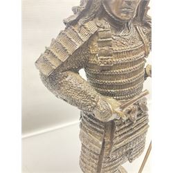 Bronze figure of a samurai standing wearing armour and holding a naginata, upon a rocky base, H48cm