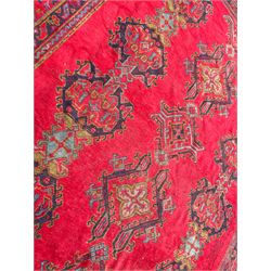 Early 20th century Western Anatolia Turkish Oushak crimson ground carpet, the field decorated with rows of Herati and Palmette medallions, the main border decorated with stylised flower head motifs within guard stripes