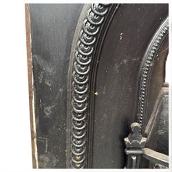 Late Victorian black-painted cast iron fireplace, the arched surround with anthemion cartouche and guilloche-moulded border, enclosing a bow-front fire basket with finialled standards, railed front and leaf-cast apron, with sheet-metal backplate