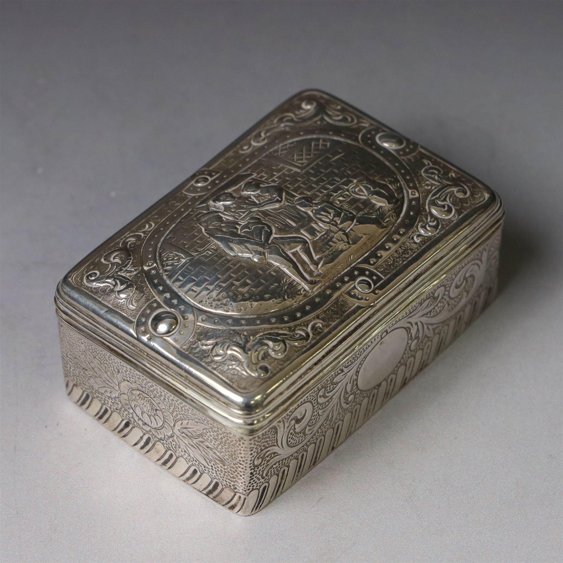 19th century Continental silver box, of rectangular form, the lift off cover with repousse figural scene, the base chased with vacant panels, acanthus scrolls and flower heads, unmarked, H4.5cm W8.5cm D5.5cm