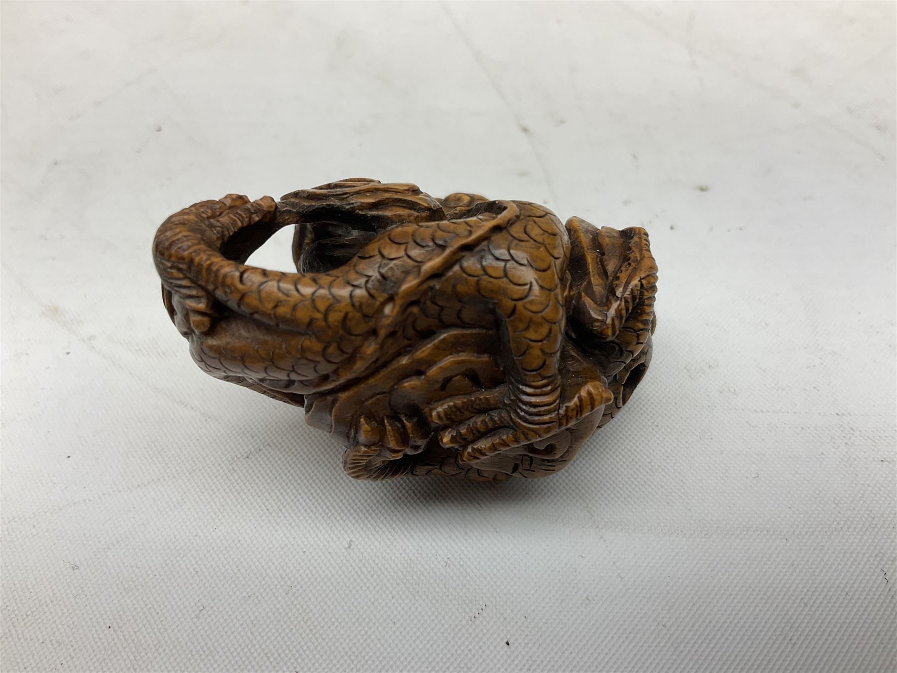 Hardwood bust of an Indoniesian Goddess, carved wearing a pierced headdress, from Klungkung, Bali, H20cm, together with a pair of bone carvings of deity figures, and a carved wood Netsuke in the form of a Chinese dragon