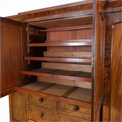 Early 19th century figured mahogany combination wardrobe, the breakfront architectural cornice over central press cupboard enclosing linen slides, flanked by full-height hanging cupboards with arched inset panels, lower arrangement of two short and two long drawers with turned knob handles, applied acanthus carved detail, raised on bun feet