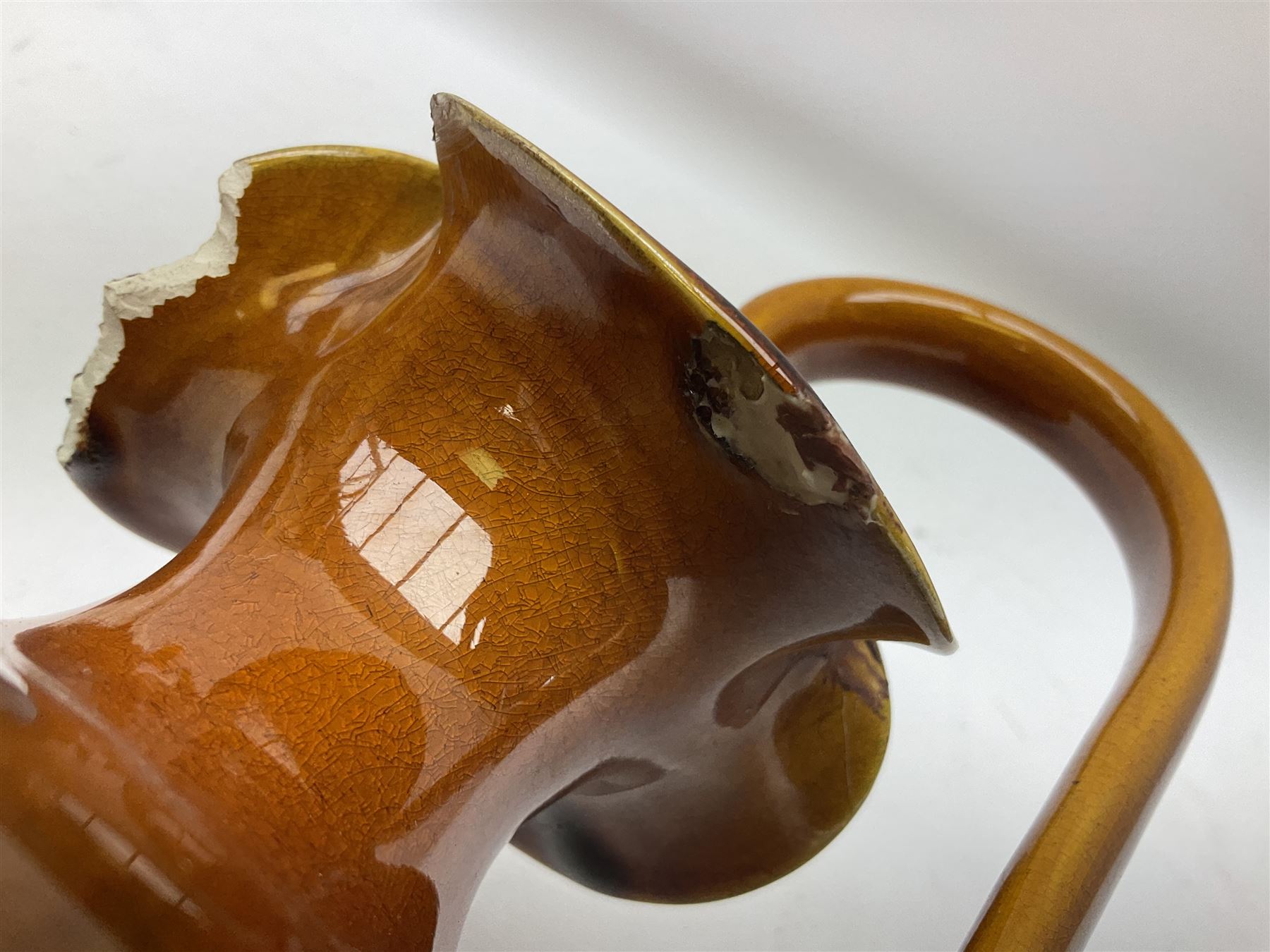 Linthorpe pottery vase with crimped rim and ovoid body, Linthorpe jug with high loop handle and crimped spout, a pair of candlesticks with a green, brown glaze and other similar pottery 