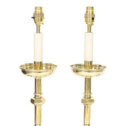 Pair of early 20th century brass alter candlesticks converted to table lamps, each with stepped and spreading circular base leading to a double hexagonal knopped column, and plain socket above inverted domed circular drip pan, the socket with light fitting, overall H49cm